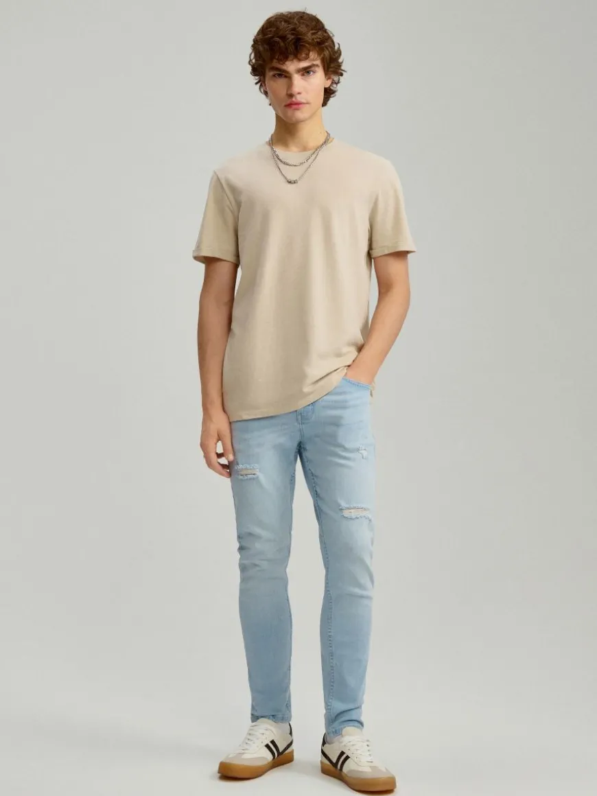 Jasnoniebieskie jeansy carrot fit z efektem sprania i przetarciami